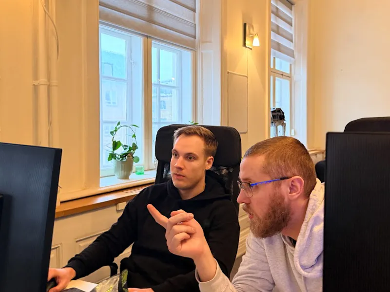 Två Devay-konsulter parprogrammerar vid skärmen på kontoret